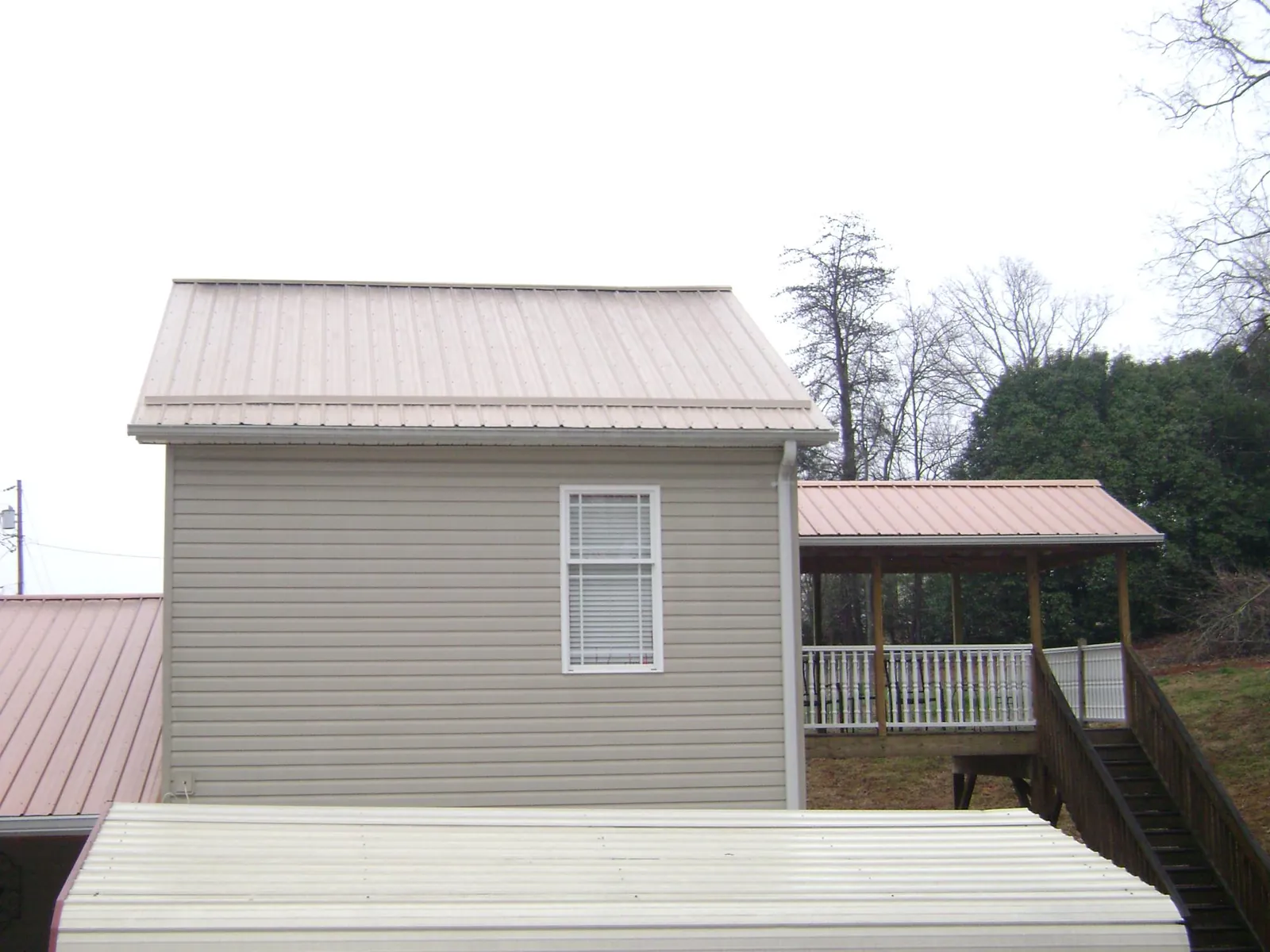 Tan metal roofs on a two story addition and attached porch, from a Roof Replacement job in Wallace