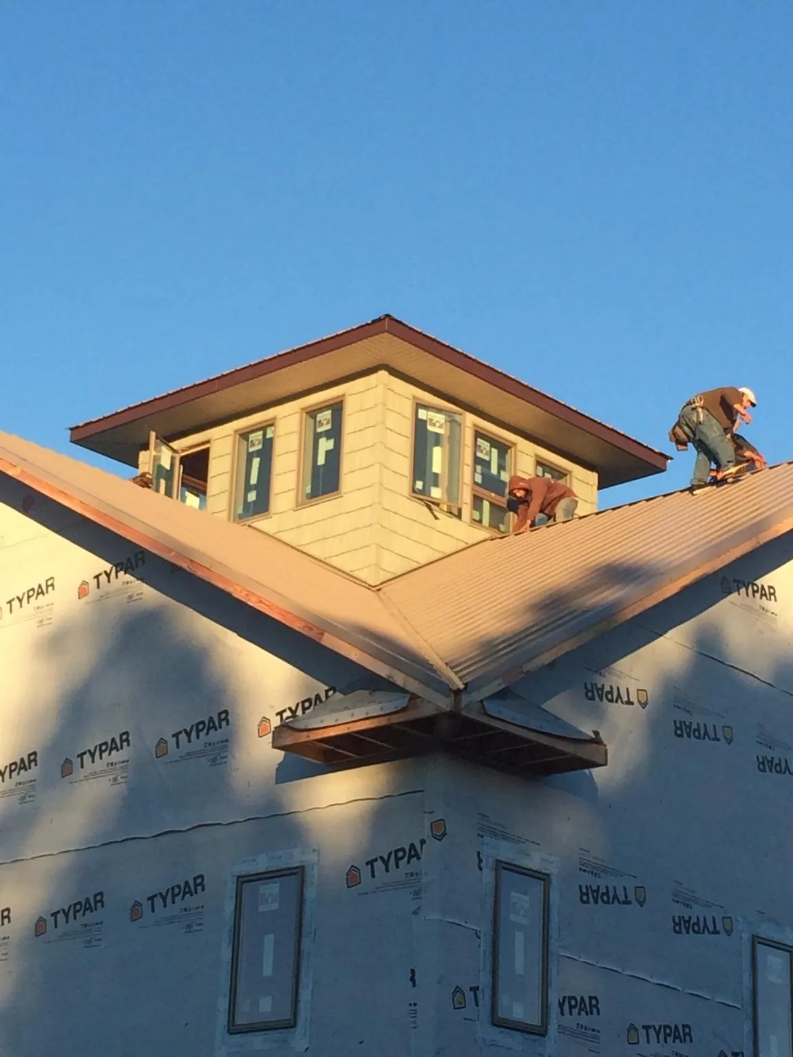 Roofers working around a rooftop cupola on a new metal roof at sunset — Roof Waterproofing in Wallace by Roofing Brothers